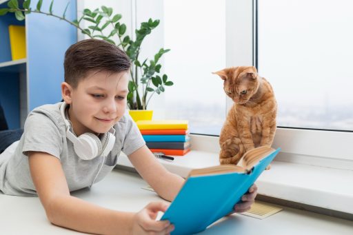 Child reading a book while a cat looks on